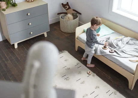 toddler standing next to bed