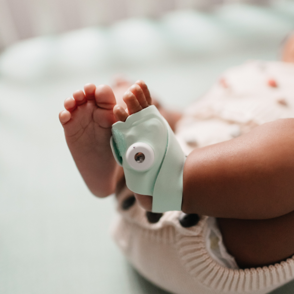 Baby's foot wearing a green Dream sock
