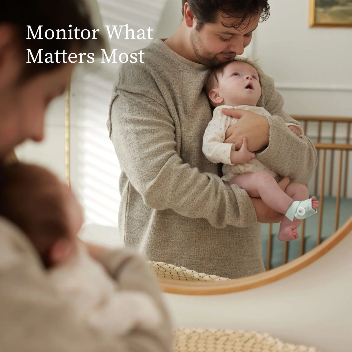 Man holding a baby with text 'Monitor What Matters Most' in a home setting.