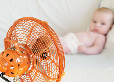 baby laying in front of a fan