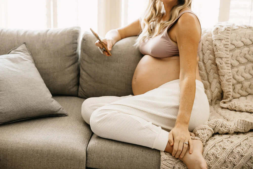 Pregnant female sitting on couch with legs folded